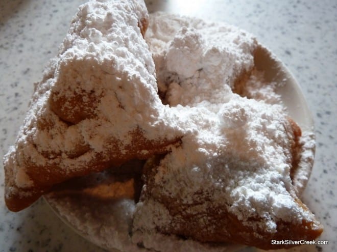 Close-up of Beignets Three hot beignets covered in powdered sugar on a plate