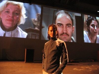 During a rehearsal, director Kim Collier stands on the No Exit set, with the cast on screens. Photo by Nathan Medd.