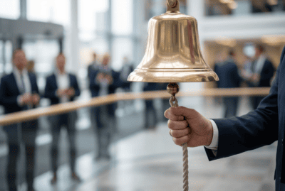 A hand rings the opening bell on a stock exchange trading floor as OpenAI and Anthropic head to the public markets