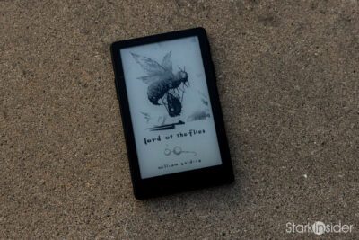 XTEINK X4 Pro pocket e-reader resting on sand, its e-ink sleep screen displaying the cover art for William Golding's Lord of the Flies
