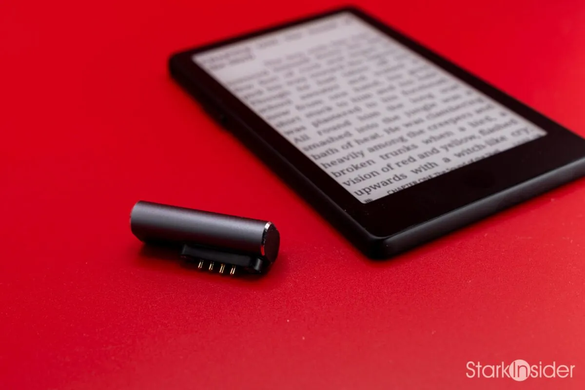 The XTEINK X4 Pro's magnetic pogo-pin charging adapter detached and resting beside the device, which displays a page of text from Lord of the Flies