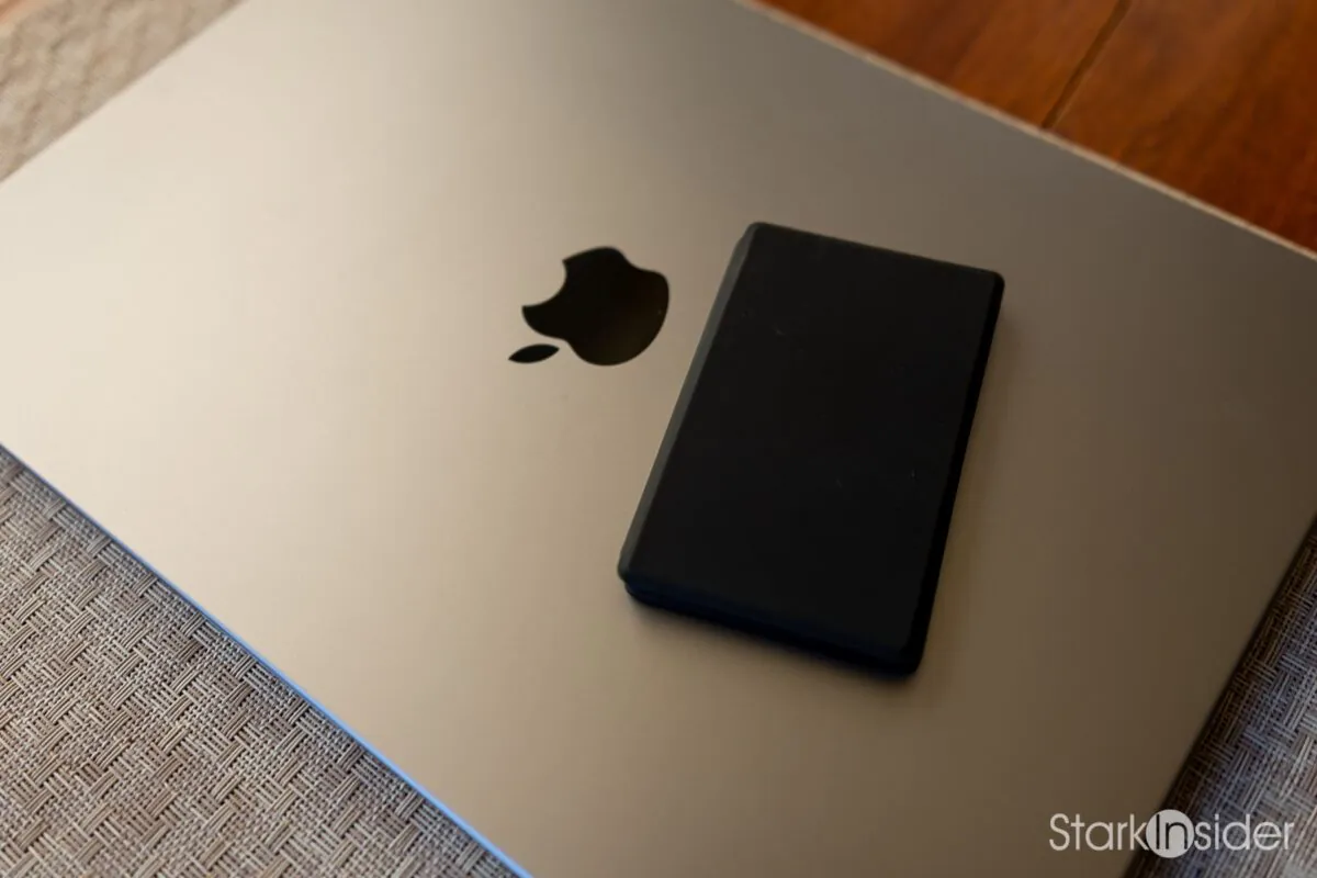 XTEINK X4 Pro pocket e-reader resting closed on the lid of a MacBook Pro next to the Apple logo, showing how small the device is compared to a laptop